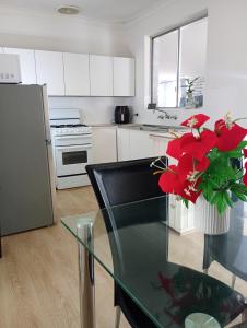 a kitchen with a glass table with a vase of red flowers at Budget Friendly Accommodation in Mandurah