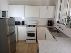 a white kitchen with a stove and a sink at Budget Friendly Accommodation in Mandurah