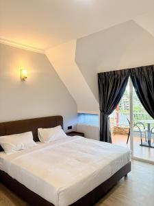 a bedroom with a large white bed and a window at Kea Garden Guest House in Brinchang