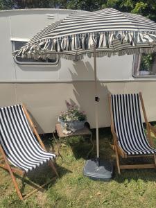 two chairs and an umbrella in front of a trailer at The running Rabbit caravan in Ystad
