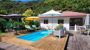 a house with a wooden deck and a swimming pool at Sweet little house - private pool in Punaauia