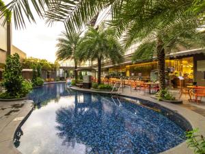 a large swimming pool with palm trees in a building at Ibis Styles Singapore On Macpherson in Singapore