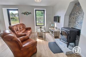 a living room with a leather couch and a fireplace at Ty prad in Lanvellec