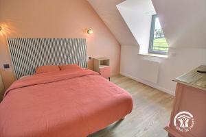 a bedroom with a bed with an orange comforter and a window at Ty prad in Lanvellec