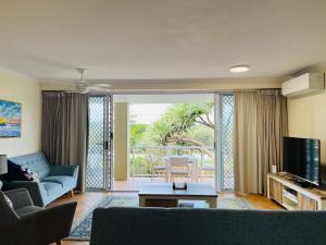 a living room with a couch and a tv at Horizons At Peregian in Peregian Beach
