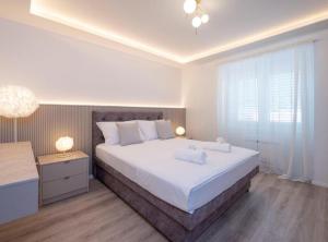 a bedroom with a large white bed and a window at Apartman Dolce in Trpanj