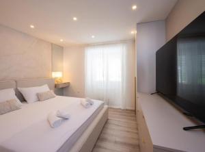 a bedroom with a large white bed with a flat screen tv at Apartman Dolce in Trpanj