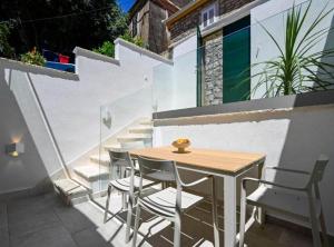a wooden table and chairs on a balcony with stairs at Apartman Dolce in Trpanj