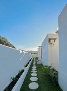 a walkway between two white buildings with grass at Garden Hill Kintamani with Natural Hot Springs in Kubupenlokan