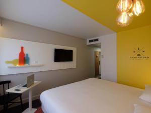 a bedroom with a bed and a desk with a laptop at Hôtel ibis Styles Auxerre Nord in Auxerre