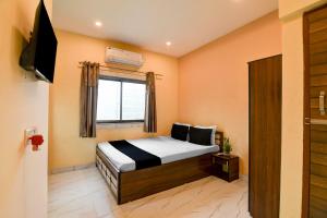 a bedroom with a bed and a window and a television at Hotel O Agarpara Railway Station Road Formerly Chowdhury Guest House in kolkata