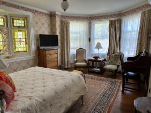 a bedroom with a bed and a television and a chair at Munroe Inn Boutique Hotel in Auburn
