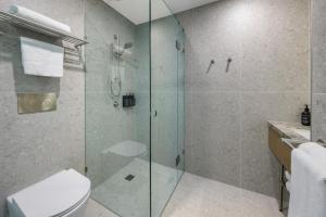 a bathroom with a glass shower and a toilet at Brady Hotels Elizabeth Street in Melbourne