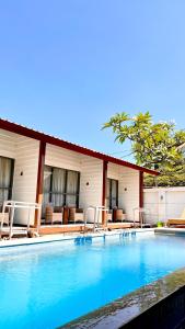 a swimming pool with chairs and a building at Villa PhyPhy in Gili Trawangan