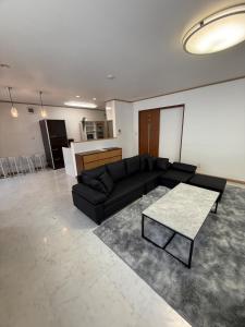 a living room with a black couch and a table at Gold rich 2 in Asahikawa