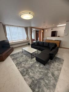 a living room with a black couch and a rug at Gold rich 2 in Asahikawa