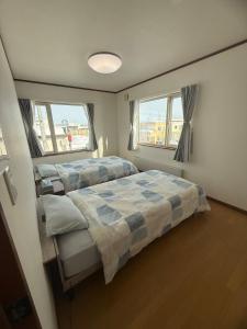 a bedroom with two beds and two windows at Gold rich 2 in Asahikawa