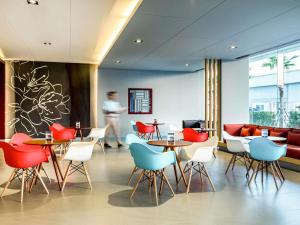 a restaurant with tables and chairs and a woman walking by at ibis Bangkok IMPACT in Nonthaburi