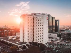 a tall white building with the sun setting behind it at Ibis Poznan Centrum in Poznań
