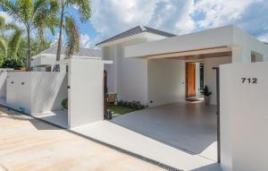 a white house with a white fence and palm trees at Luxury B Baya Pool Villa in Ban Chong Phli
