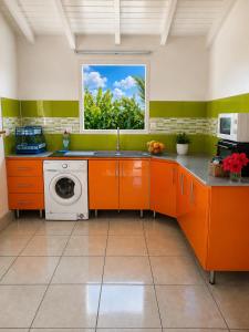 an orange kitchen with a sink and a window at O baobab in Saint-François