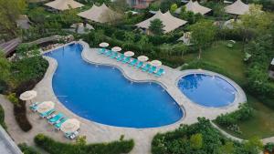 an overhead view of a pool with chairs and umbrellas at JW Marriott Ranthambore Resort & Spa in Sawāi Mādhopur