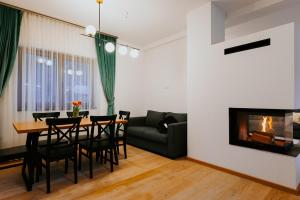 a living room with a table and chairs and a fireplace at Lucy Villa in Băile Tuşnad