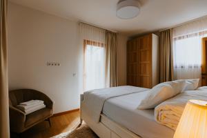 a bedroom with a bed and a chair and a window at Lucy Villa in Băile Tuşnad