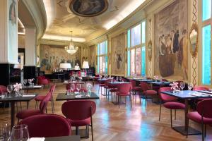 a dining room with tables and chairs and paintings on the walls at Grand Hotel Palace Rome in Rome