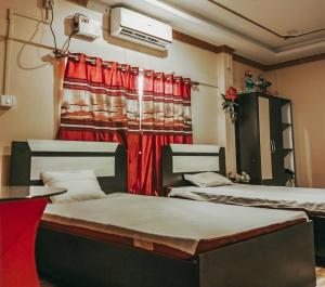 two beds in a room with a red curtain at Madhuban Resort in Silchar