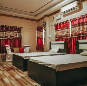 two beds in a room with red curtains at Madhuban Resort in Silchar