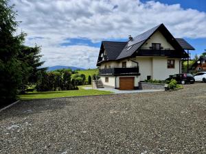 a white house with a black roof and a driveway at Apartament Pod Danielkami in Podwilk