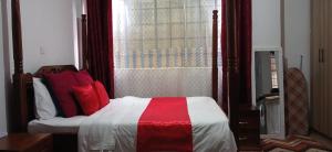 a bedroom with a bed with red and white pillows at Sunny Studio Kikuyu Town in Kikuyu +1 photo