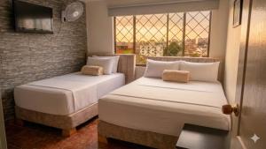 two beds in a room with a window at Hotel Iam Armenia Quindio in Armenia