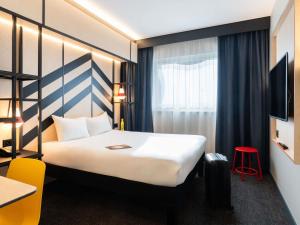 a hotel room with a white bed and a red stool at ibis Styles Geneve Palexpo Aeroport in Geneva +63 photos