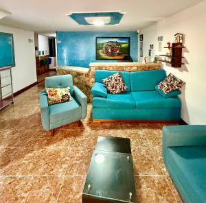 a living room with a blue couch and two chairs at Hotel Iam Armenia Quindio in Armenia