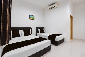 two beds in a room with white and black at Collection O Langkawi Near Pantai Cenang formerly Tokman Inn in Pantai Cenang