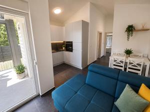a living room with a blue couch and a kitchen at Seaside Cottage Barbariga in Peroj