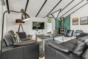 a living room with black leather furniture and a table at BV383-Blavand-Toldbodvej-34 in Blåvand
