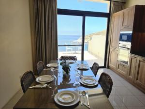 a dining room with a table and a view of the ocean at Salty Sun Seafront Penthouse in Marsalforn