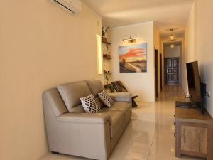 a living room with a couch and a television at Salty Sun Seafront Penthouse in Marsalforn