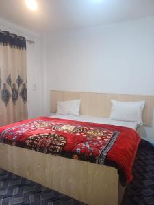 a bedroom with a large bed with a red blanket at SnowCrest Cottage in Pahalgām