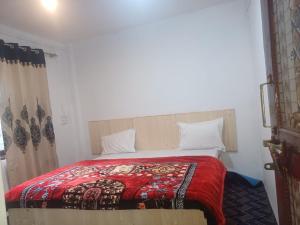 a bedroom with a bed with a red blanket at SnowCrest Cottage in Pahalgām
