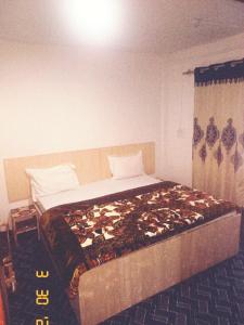 a bedroom with a large bed with a bedspread with shoes on it at SnowCrest Cottage in Pahalgām