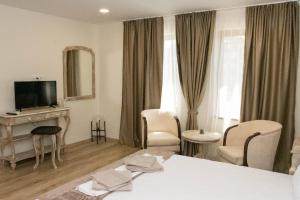 a hotel room with a bed and a television at Хотел Терес in Kazanlŭk