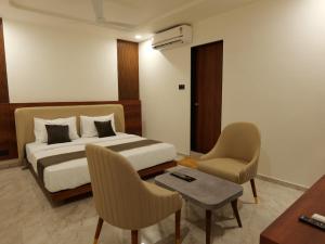 a hotel room with a bed and a table and chairs at Hotel Aqua in Rajkot