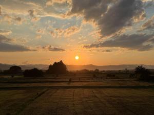 a sunset with the sun setting in a field at Hotel The Namie Terrace in Namie +12 photos