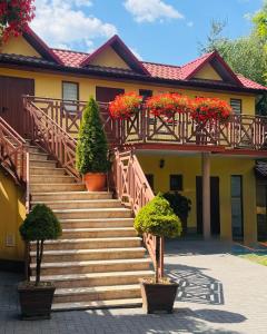 a yellow house with stairs with red flowers in pots at Willa Słoneczna in Okuninka