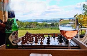 a glass of wine next to a chessboard and a bottle at The Riverside Retreat in Blakeney