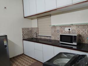 a kitchen with white cabinets and a microwave at Ocean wings Traditional beach villa in Kaipamangalam